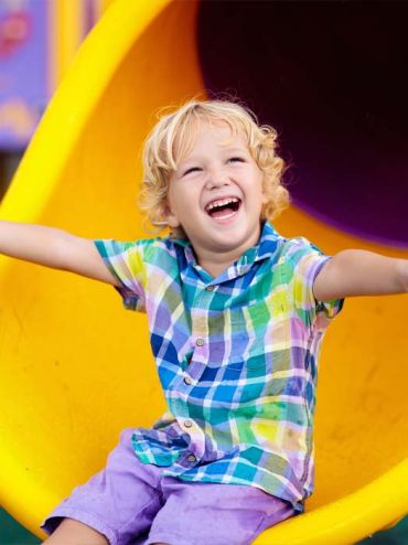 Child coming down slide smiling